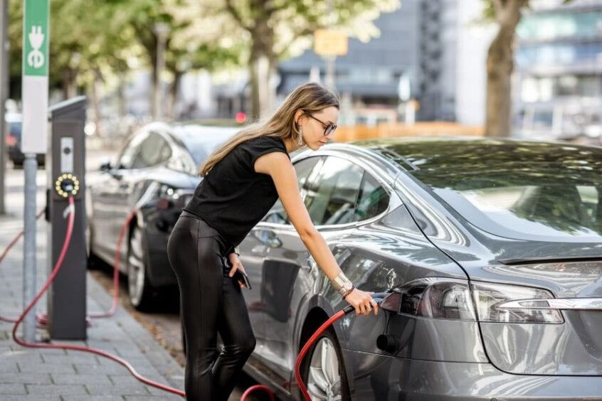 women is charging her electric car on the street parking