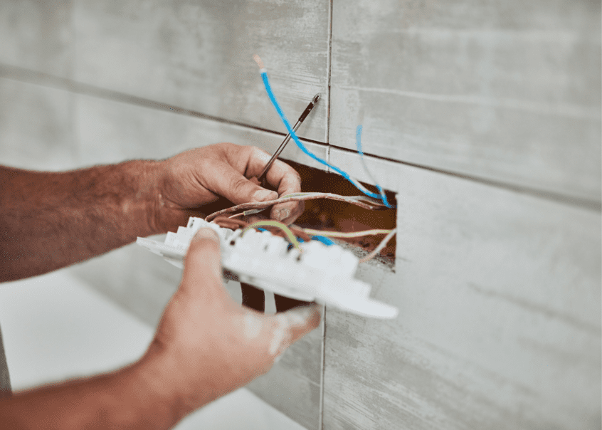 Image of electrician working with wires in wall